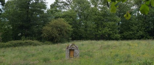 Petit puits en pierre au coeur d'une prairie bocagère marquant l'emplacement d'une source à mi-pente d'une crête gréseuse (Sainte-Suzanne) en grand format (nouvelle fenêtre)